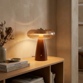 Lampe de table NALU en bois et laiton doré posée sur une console de salon